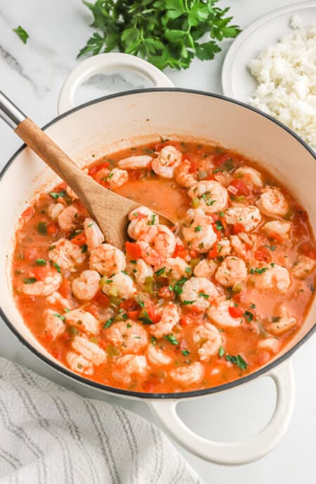 Shrimp creole being lifted out of pot with a wooden spoon