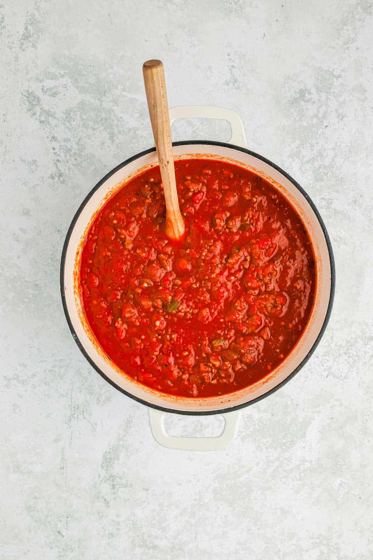 Homemade spaghetti sauce in a pot with a wooden spoon.
