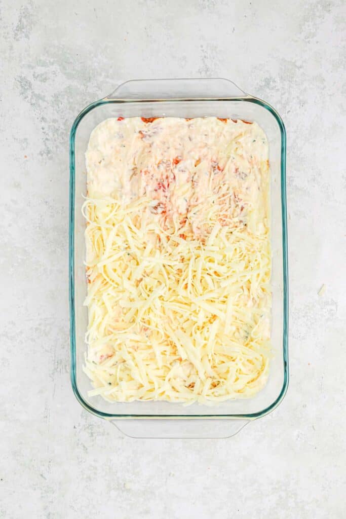 Cheese and creamy mixture on top of the spaghetti noodles in casserole dish