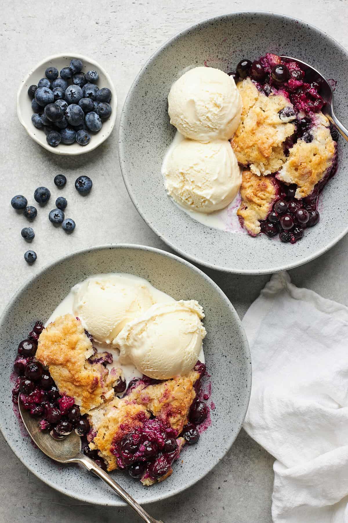 Blueberry cobbler and ice cream in a stoneware bowl.