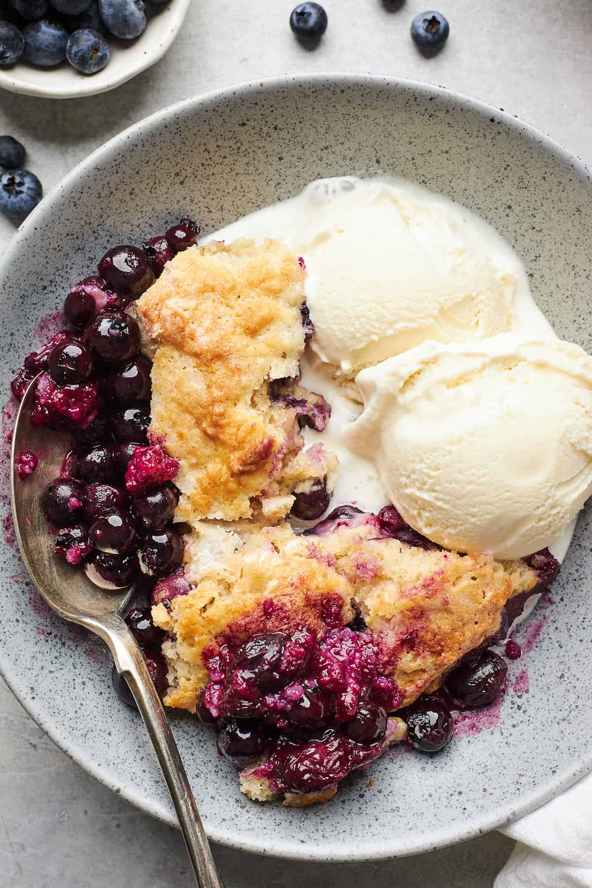 Blueberry cobbler and ice cream in a stoneware bowl.
