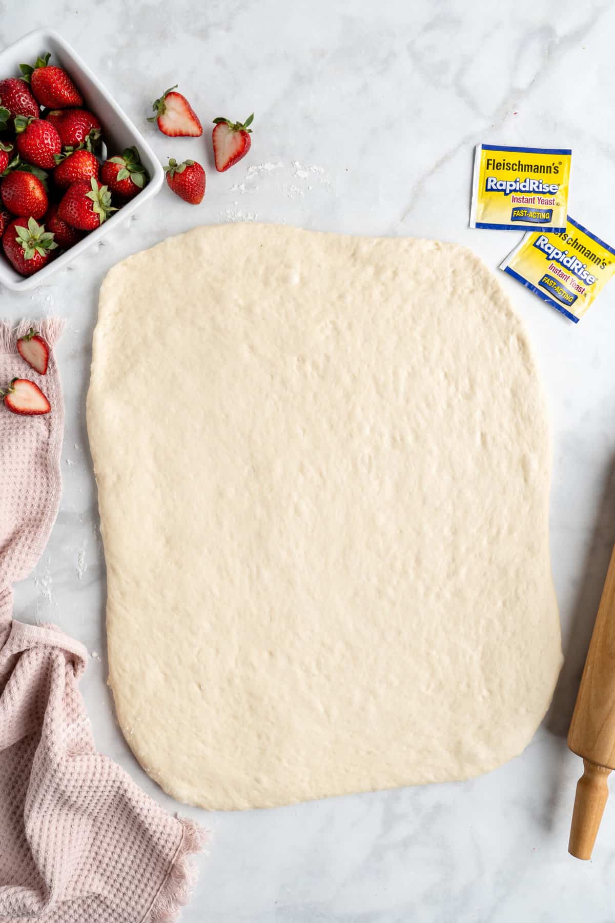Rectangle of cinnamon roll dough on a white counter.