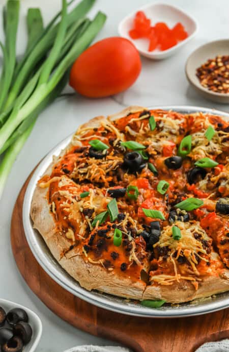 Mexican pizza on a wooden cutting board on a white background