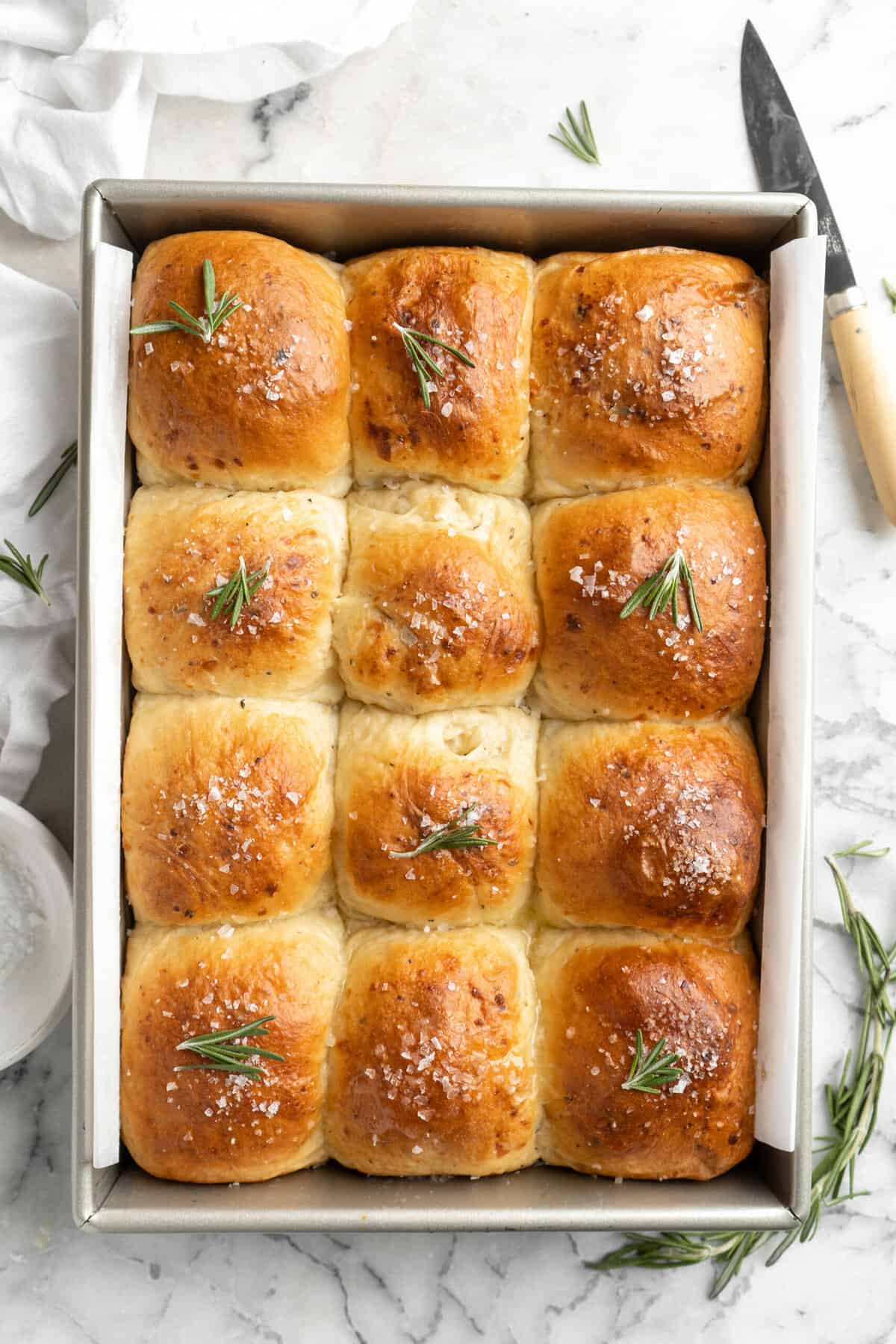 Homemade rosemary cheddar rolls in a rectangle baking pan.