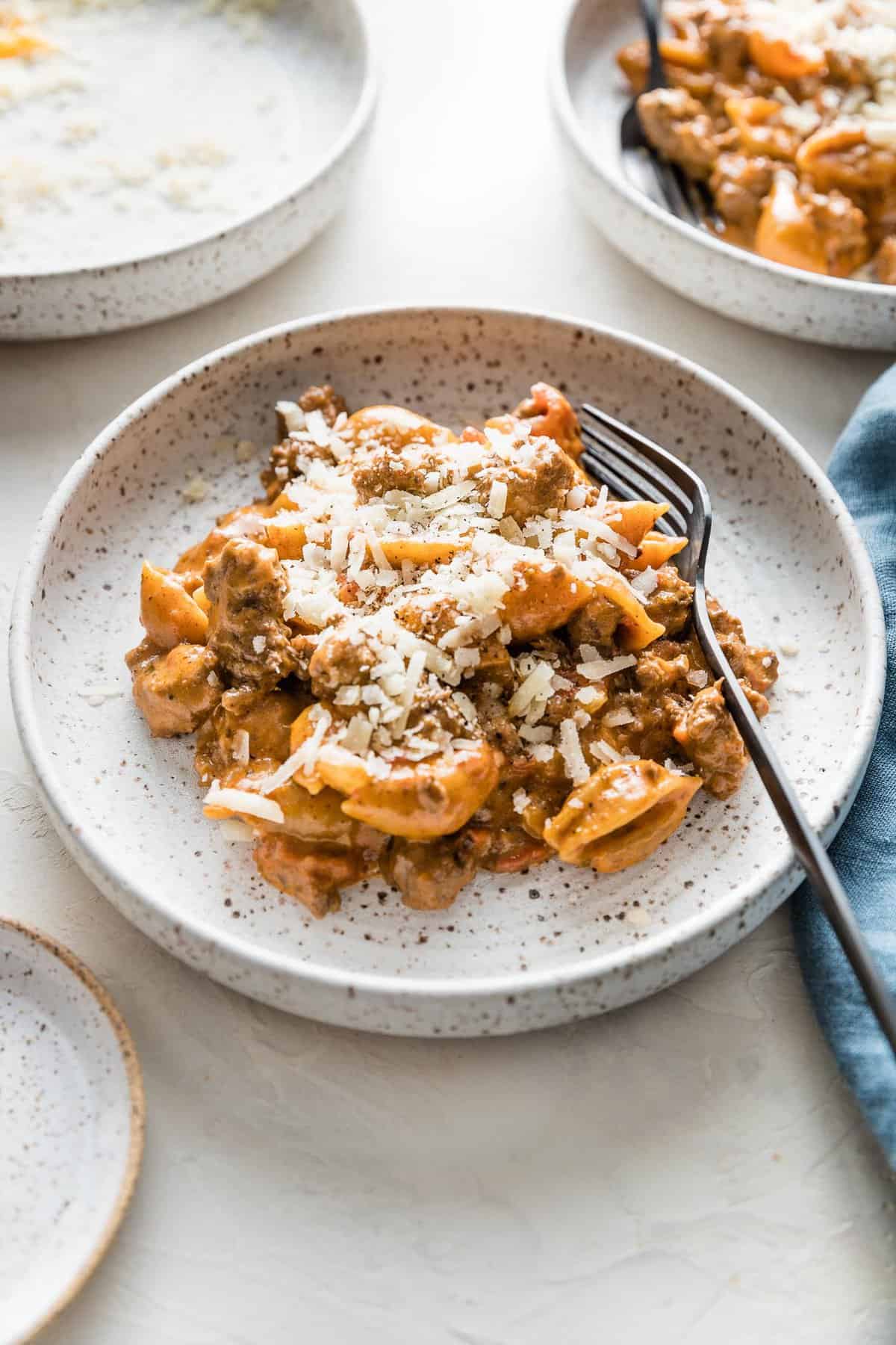 cheesy hamburger helper recipe on a white plate with a fork with a blue napkin on a white background