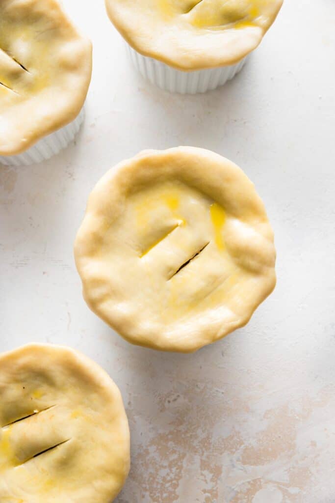 pot pies topped with dough with two slits cut into the top.