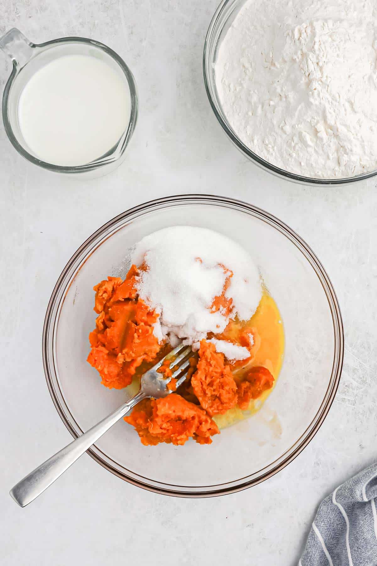 Sweet potato, egg and sugar in a mixing bowl with a fork.