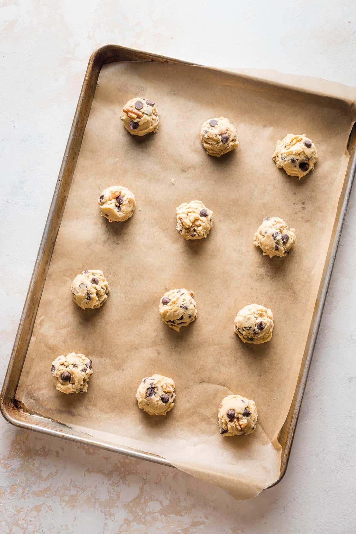 cookie dough balls on a parchment lined baking sheet