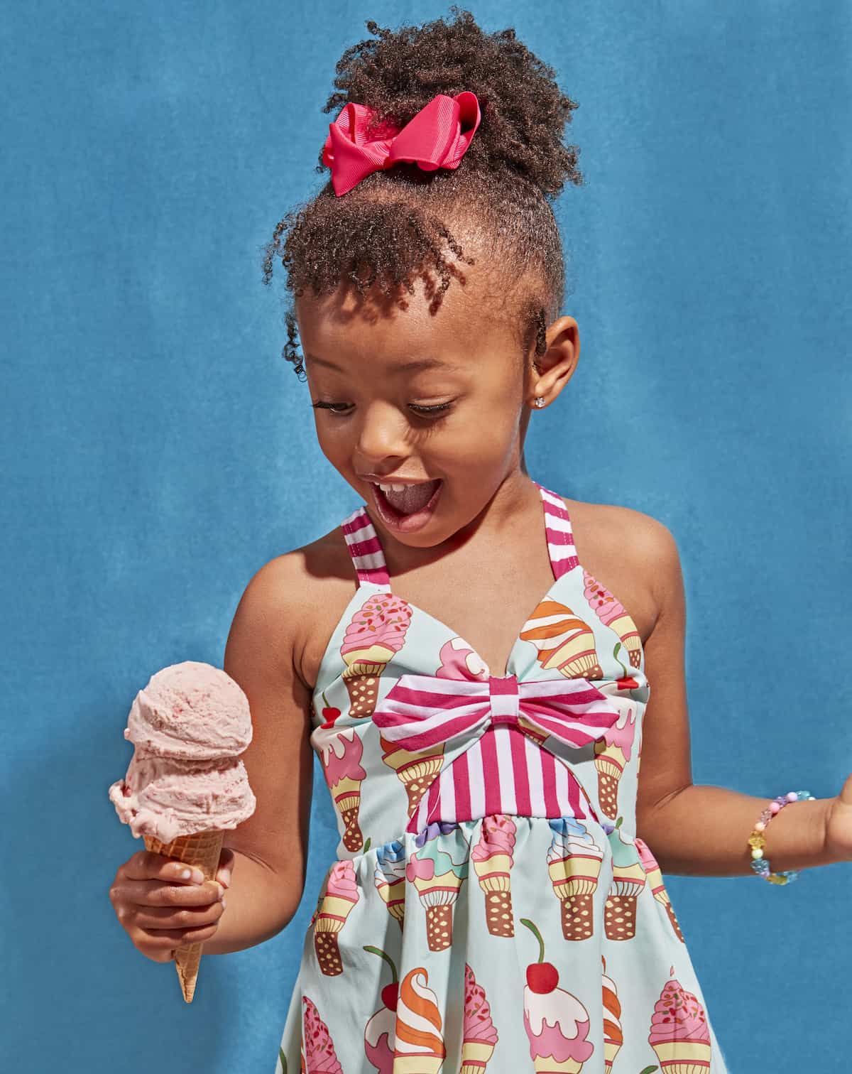 Little girl holding a strawberry ice cream cone.