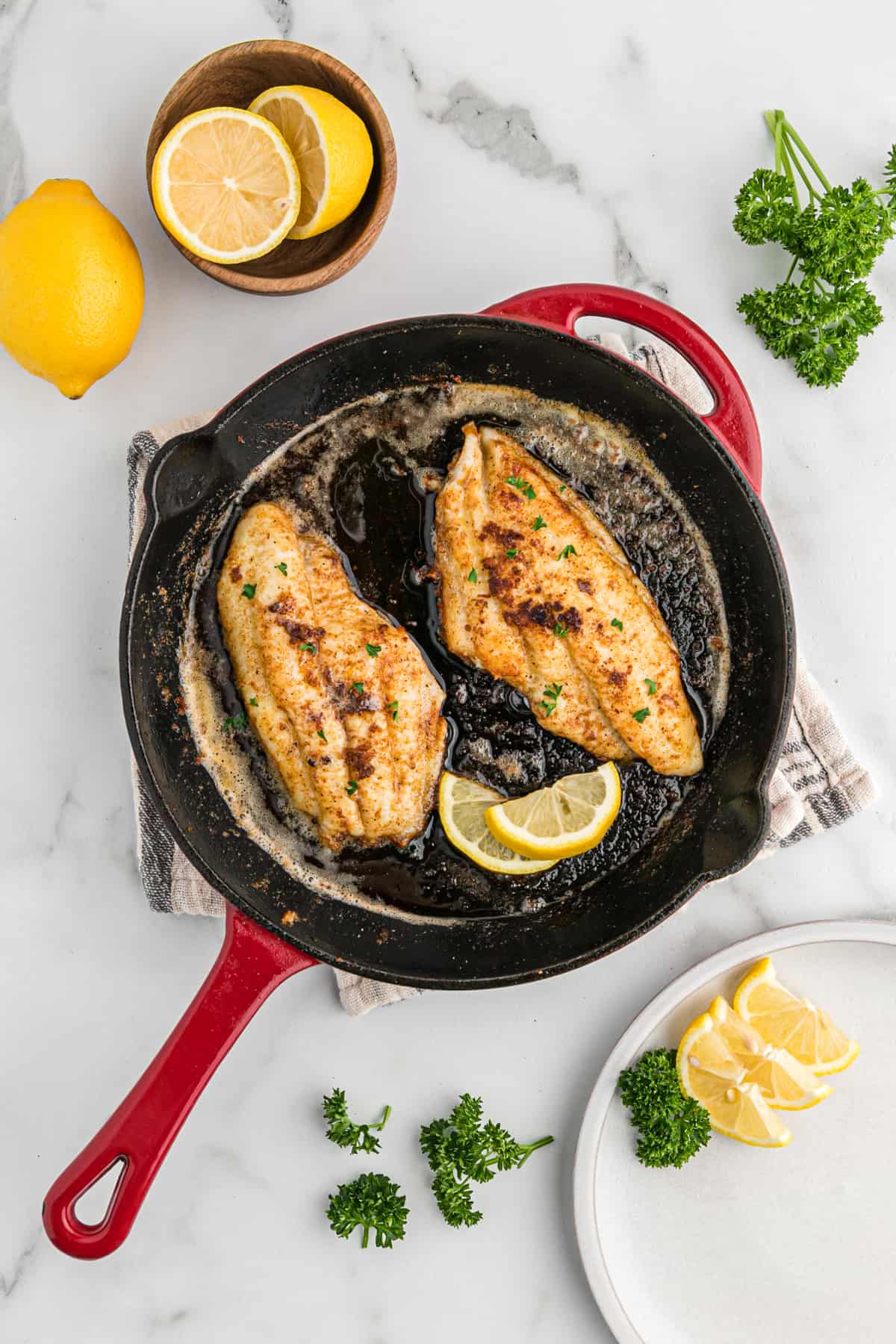 Blackened catfish filets in a red cast iron skillet.