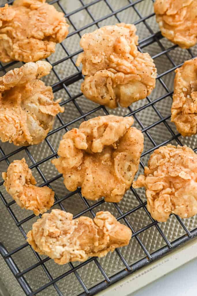 Fried oyster mushrooms draining on a wire rack.