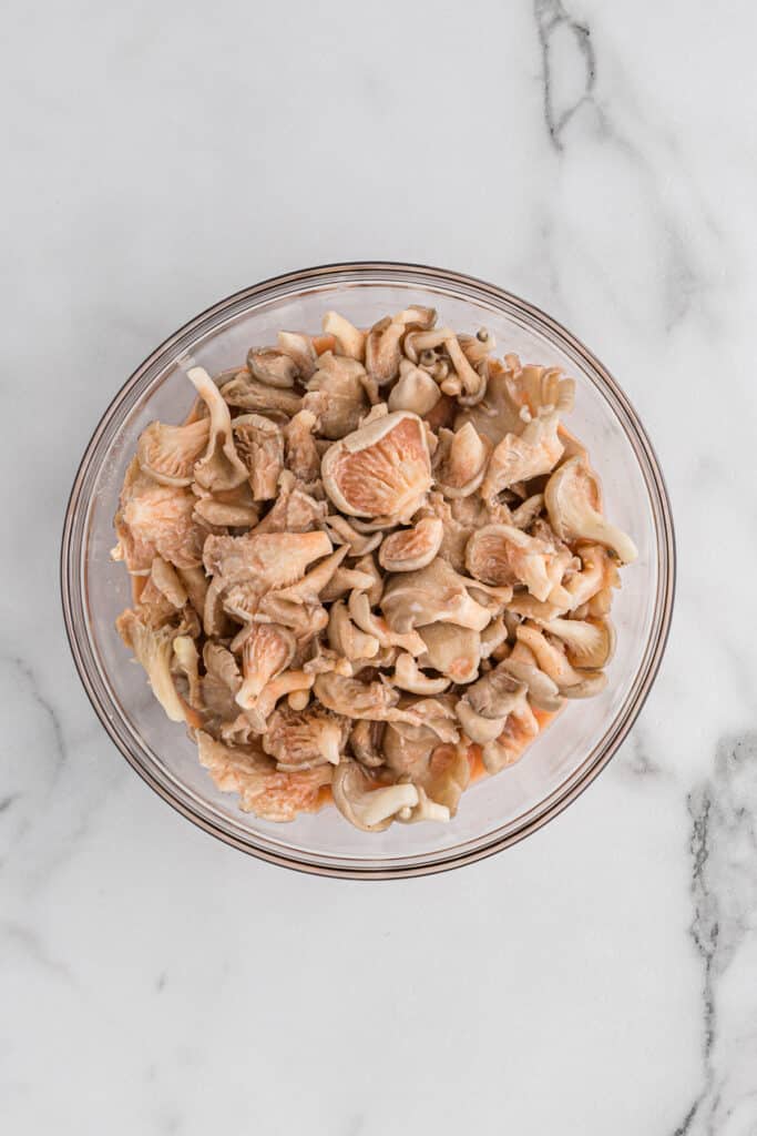 Washed oyster mushrooms in a glass mixing bowl.