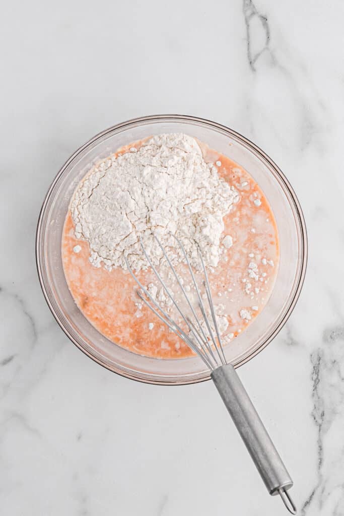 A whisk in a bowl of batter.
