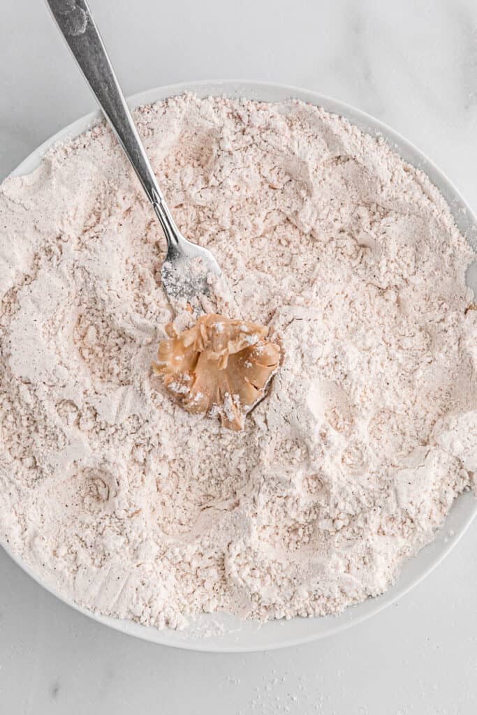 A fork placing an oyster mushroom into a plate of breading.