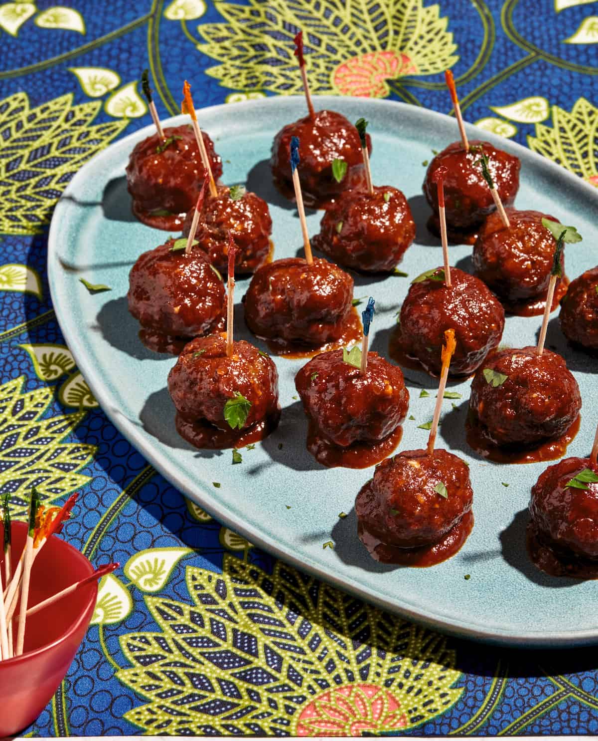BBQ Lamb Meatballs with frilly toothpicks on a blue serving platter.
