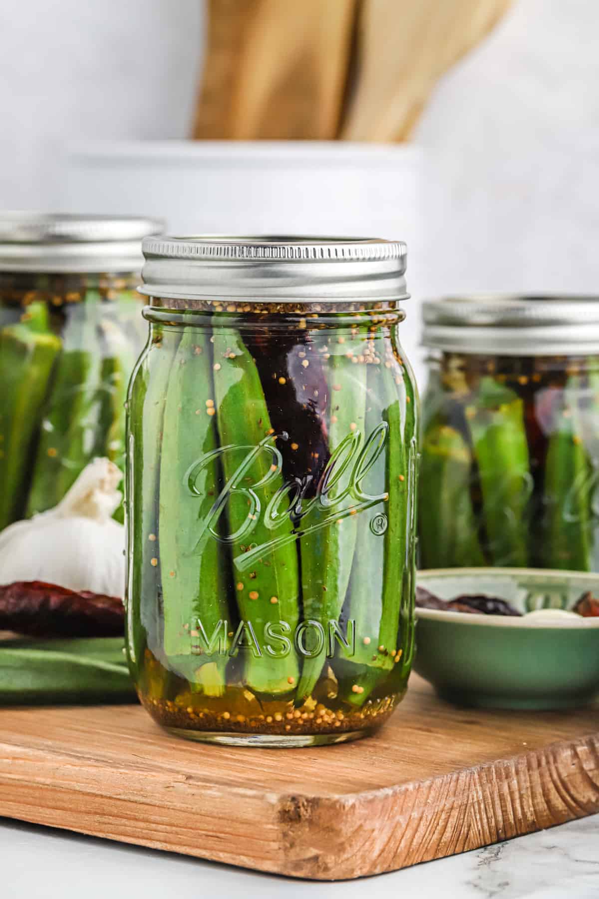 Sealed jars of pickled okra against a white backdrop.