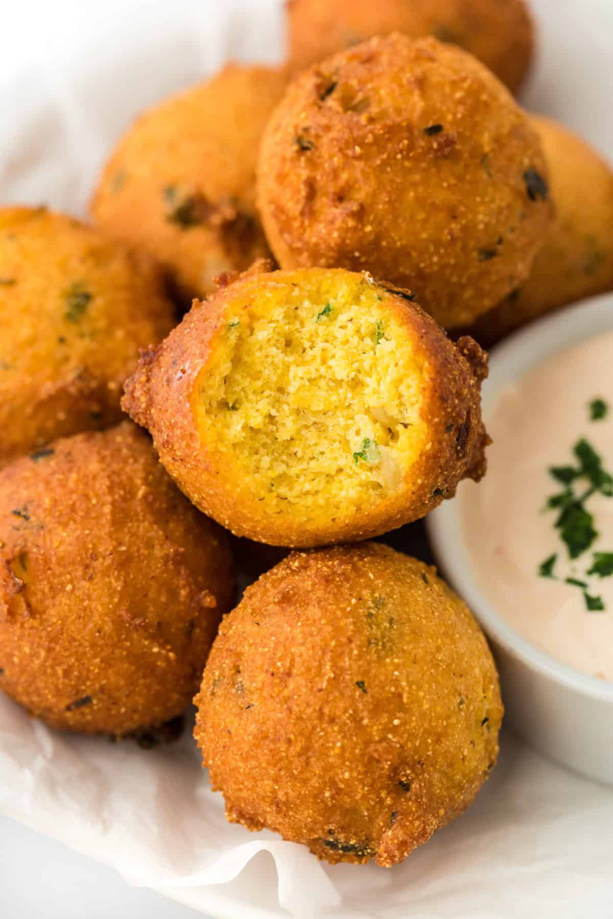 Southern hushpuppies on a white paper towel with one bitten into