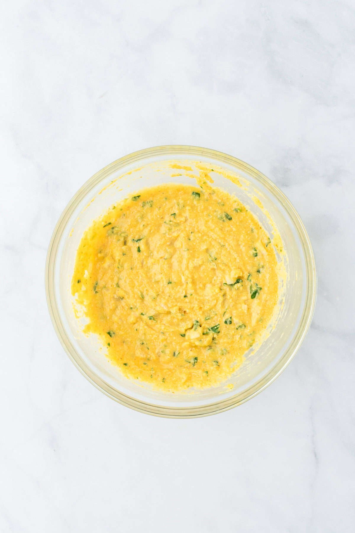 Hushpuppy recipe batter resting in a clear bowl on a white background