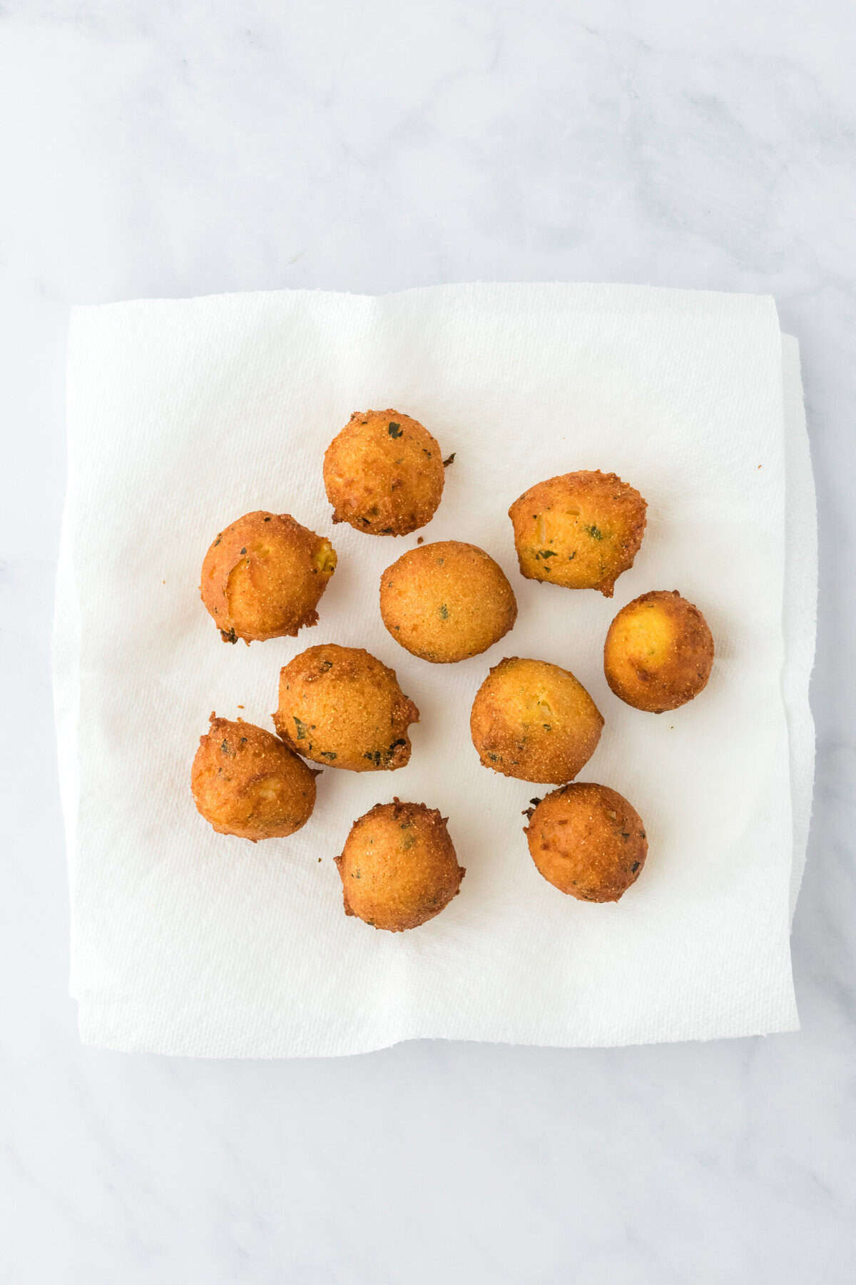 Drained hush puppies on paper towels on a white background