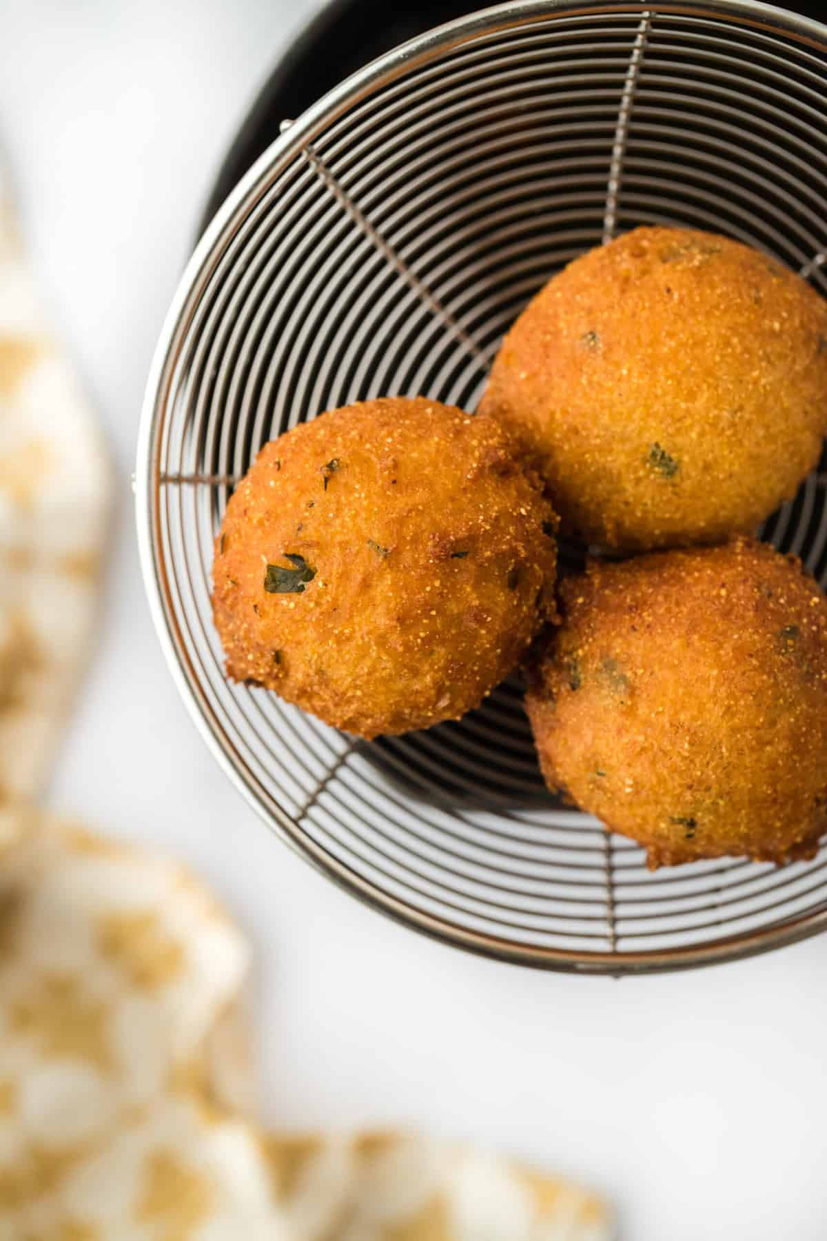 Three fried hushpuppies being removed from hot oil