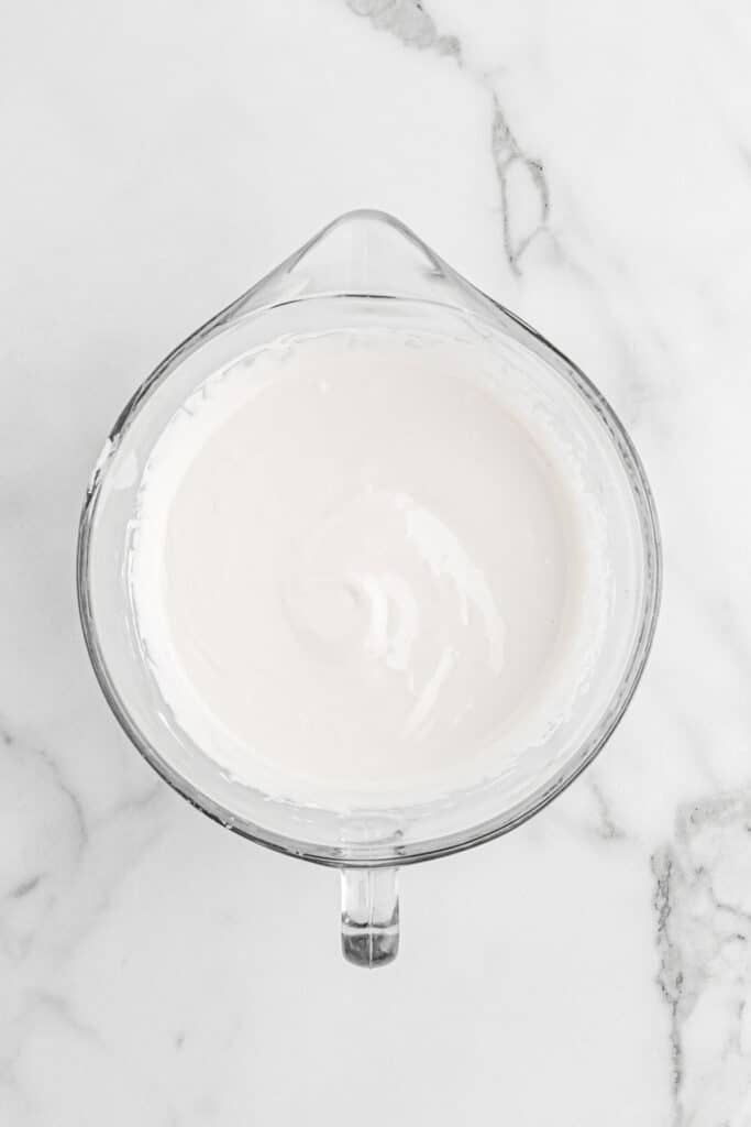 Coconut icing after being mixed in a stand mixer on white countertop