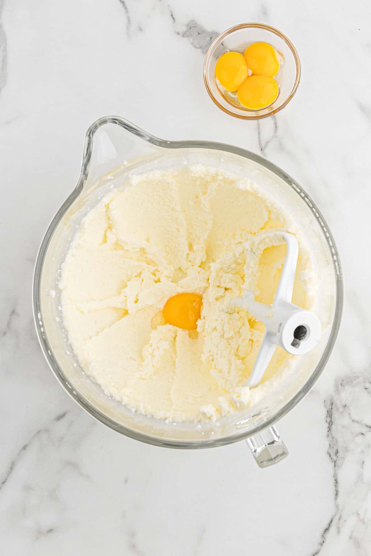 Butter and sugar mixed together in a mixing bowl with an egg added.