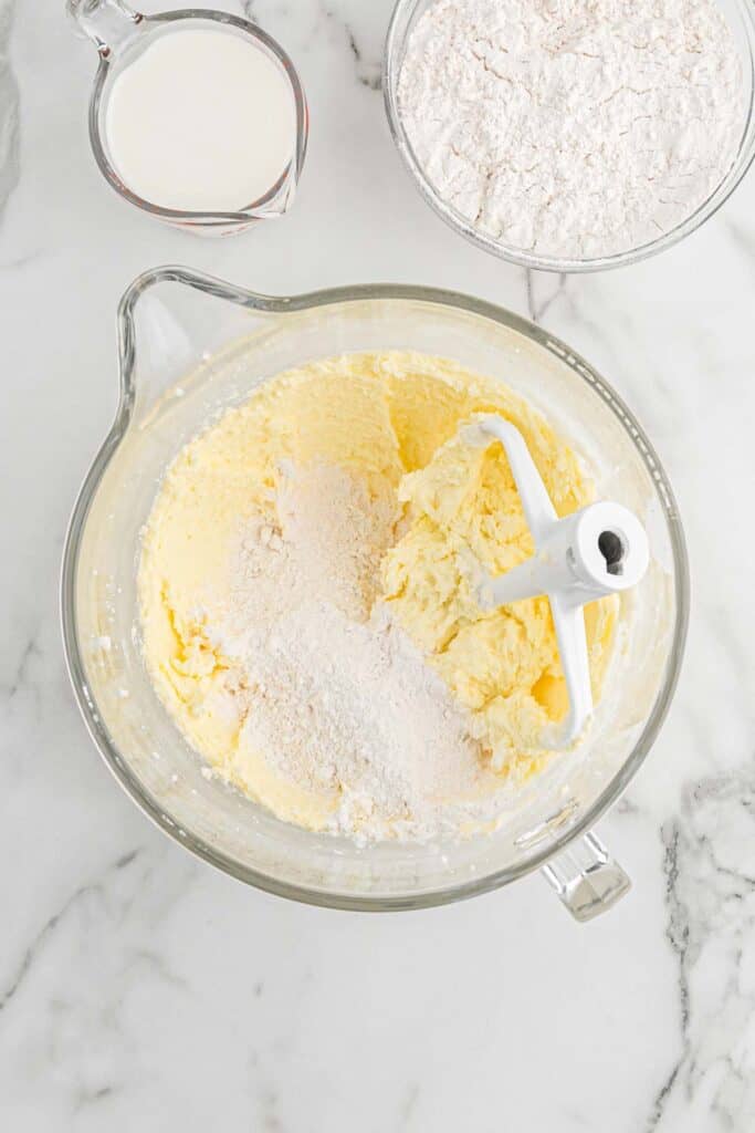 Flour added to butter and sugar and egg mixture on white countertop