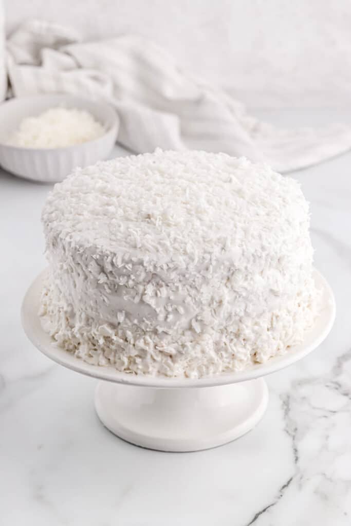 Finished coconut cake on a cake stand.