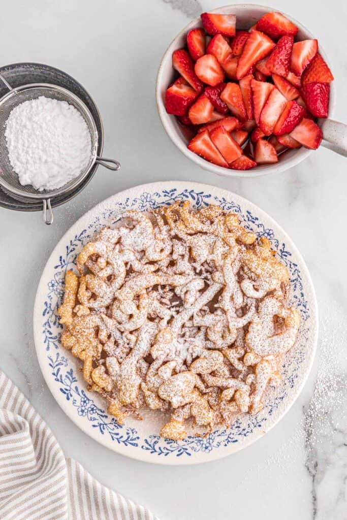 A funnel cake topped with powdered sugar on a plate.
