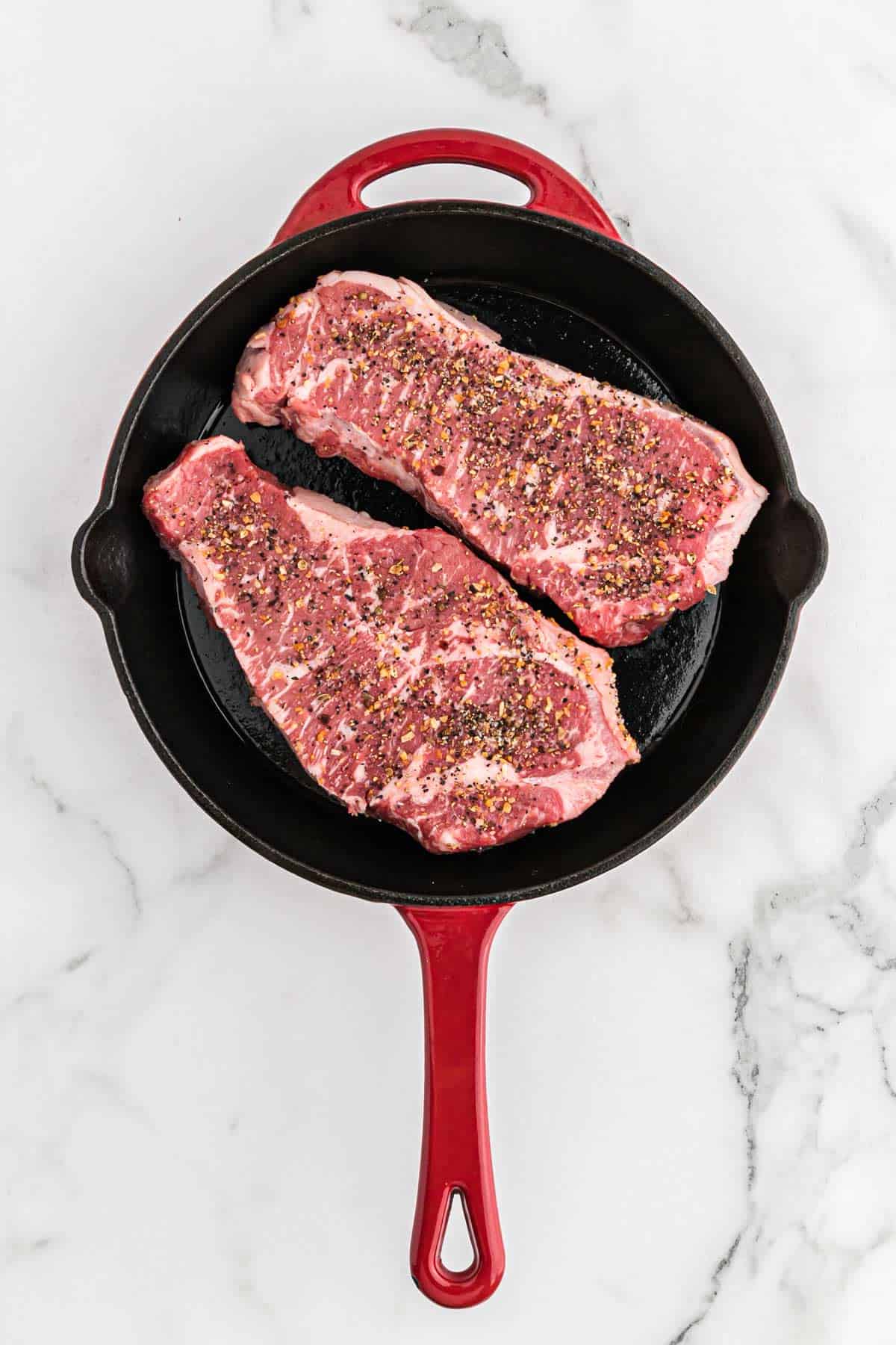 Steaks cooking in a pan.