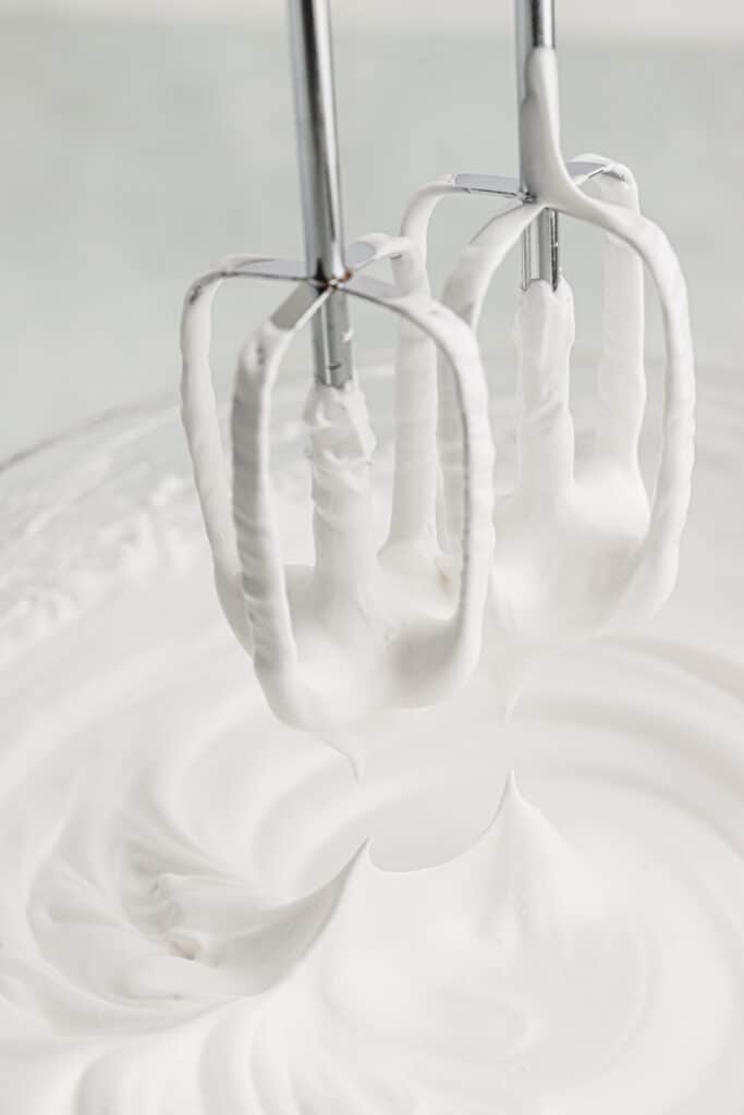 A hand mixer pulling the paddles out of the whipped frosting.