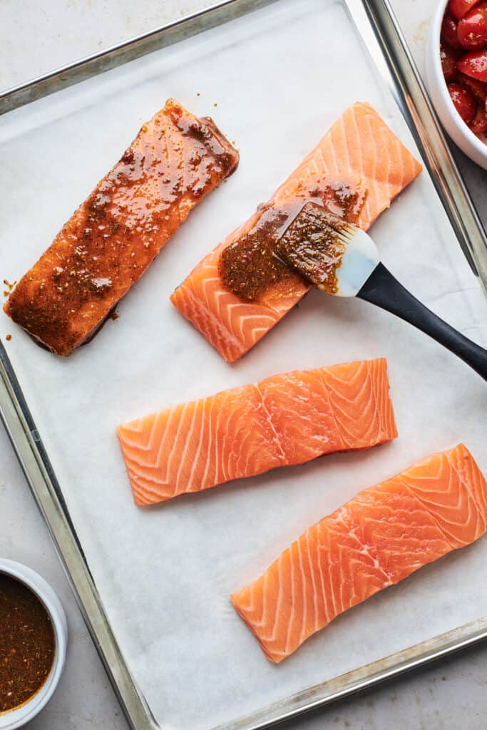 Salmon filets being brushed with jerk paste