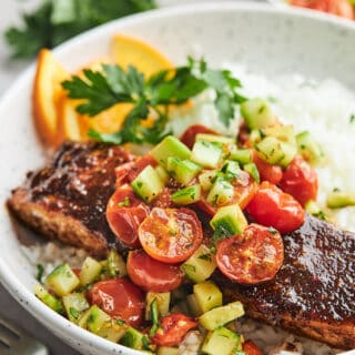 Sheet pan salmon on a plate with rice and tomato cucumber salad