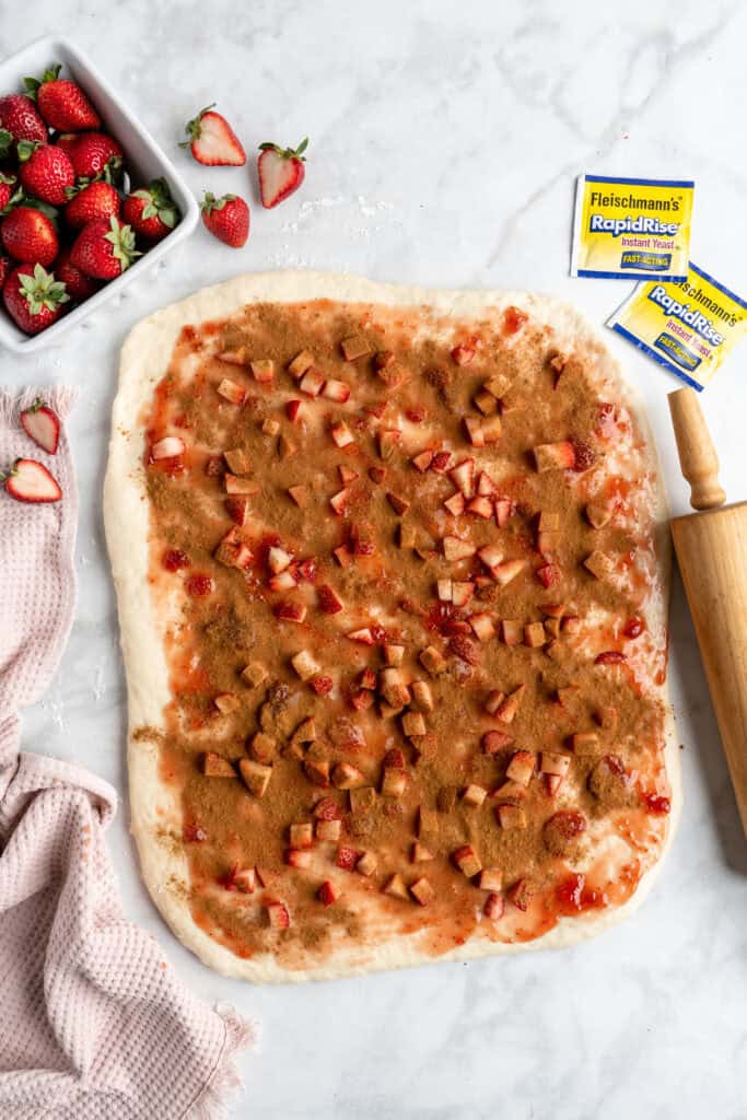 Berries, cinnamon and jam spread over cinnamon roll dough
