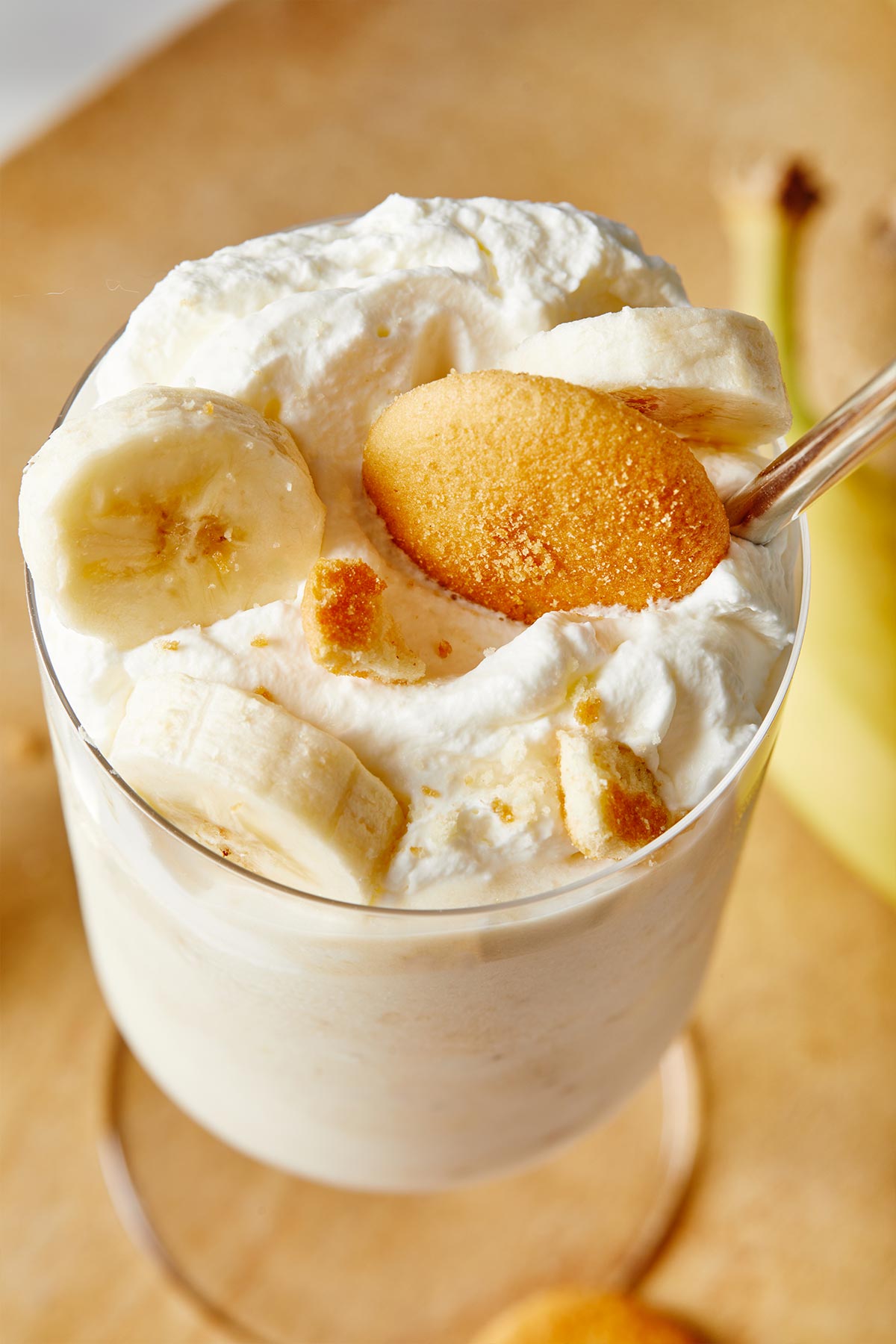 A close up of banana ice cream milkshake with some spilling over the glass ready to serve