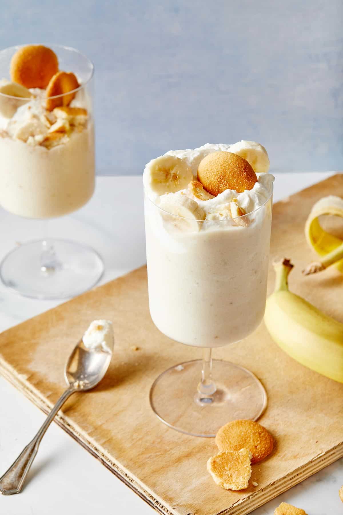 Two banana pudding milkshakes ready to serve in ice cream parlor glasses with nilla wafers on top