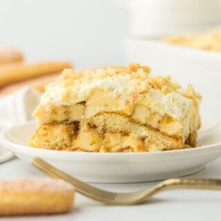 A serving of banana pudding tiramisu on a plate with ladyfingers off to the side.