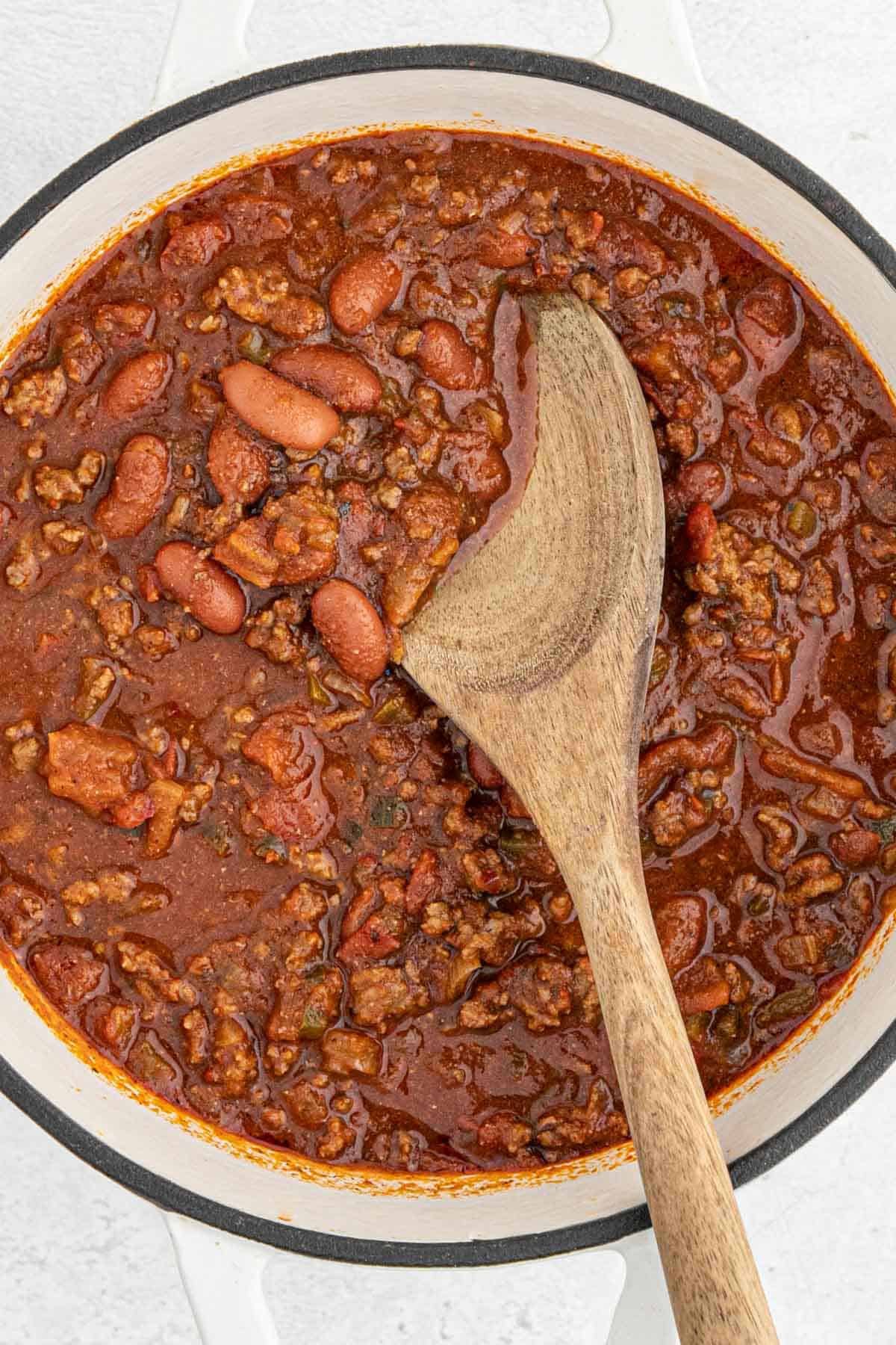 An easy chili recipe being stirred in a large dutch oven ready to serve