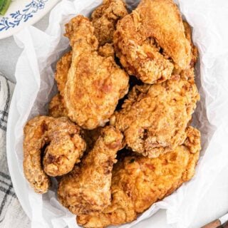 A serving bowl lined with a paper towel and filled with big mama's fried chicken on the table.
