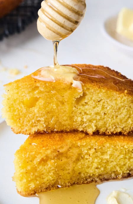 Honey and butter melting over the top of pieces of honey cornbread on a plate.