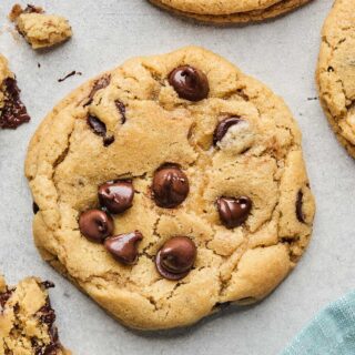 Overhead of BEST chewy chocolate chip cookie in center against white background