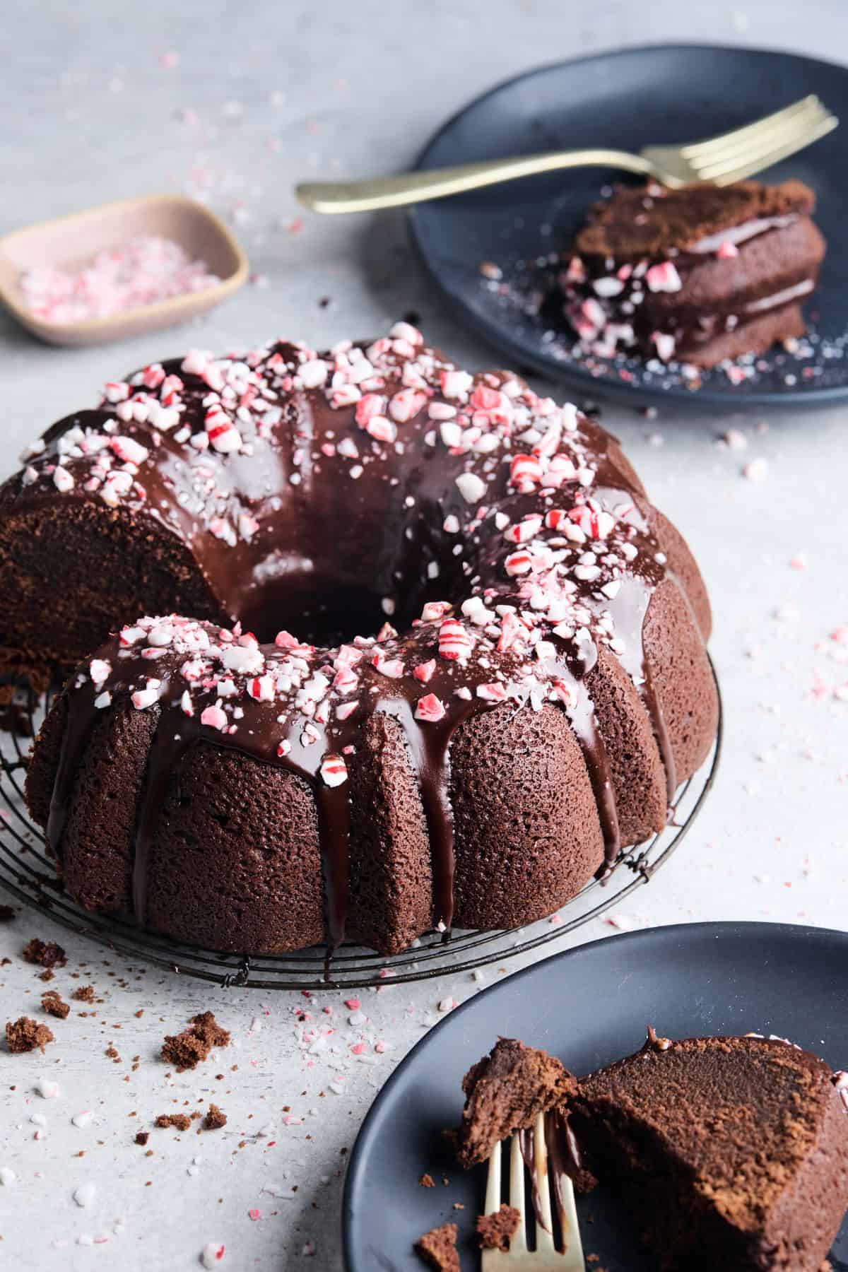 Chocolate peppermint pound cake on the table with a few pieces missing and one on a plate in the background.