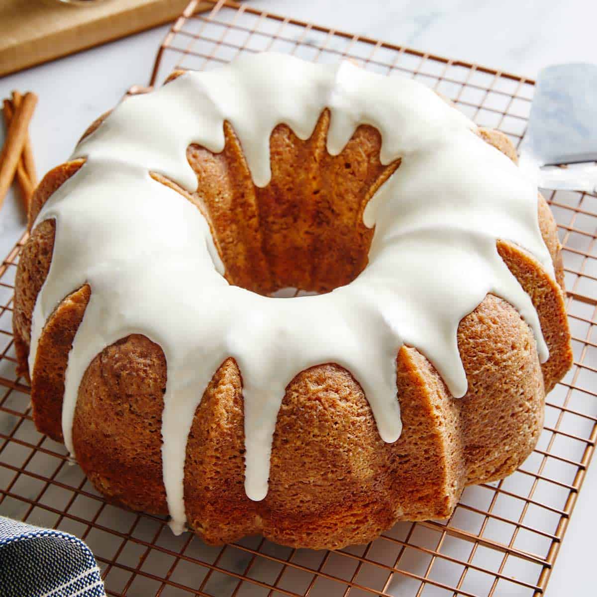 A delicious cinnamon roll pound cake on a wire rack drizzled with a glaze icing.