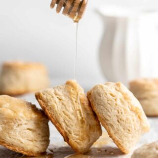 Freshly baked honey butter biscuits being drizzled with honey.