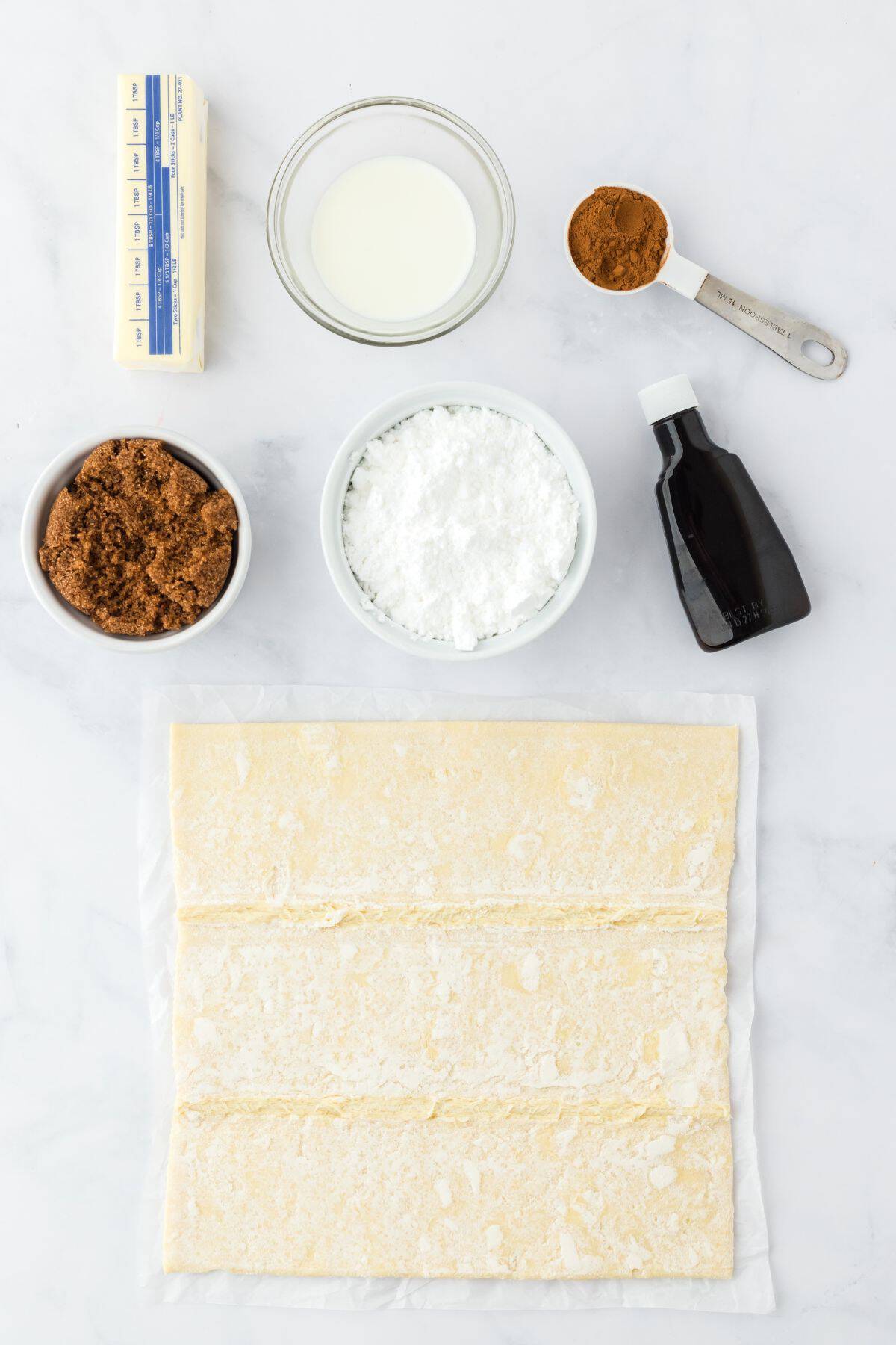 Ingredients such as brown sugar, butter, spices and puff pastry for easy cinnamon rolls.