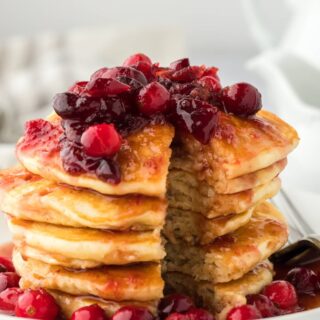 Eggnog Pancakes with Maple Cranberry Syrup cut open on a white plate