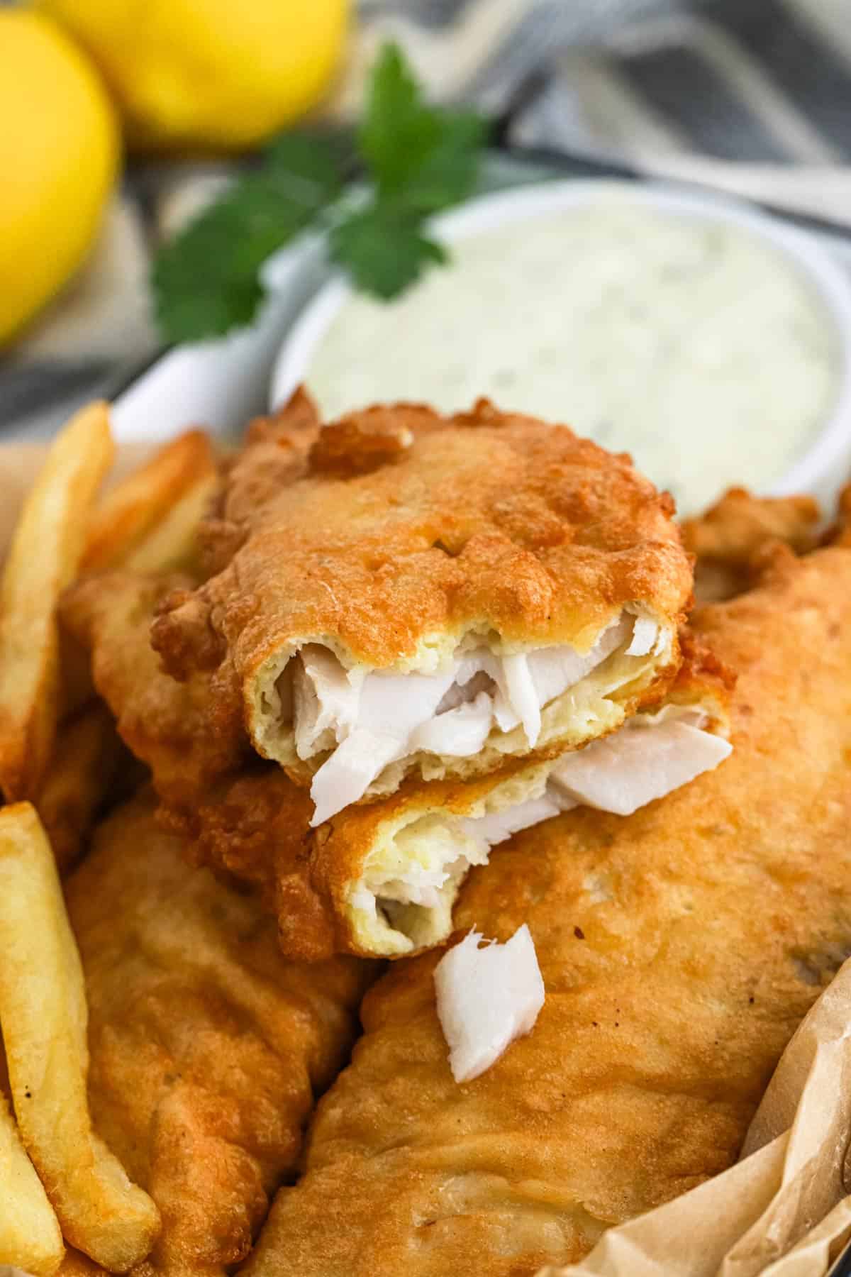 Fish and chips on a plate with the fish broken in half to show inside.