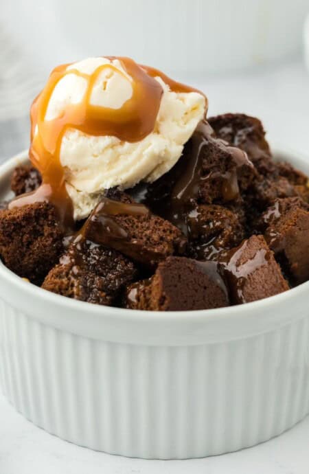 Gingerbread bread pudding in a ramekin topped with ice cream and toffee sauce.