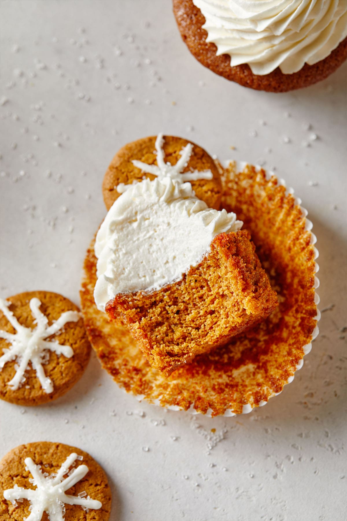 A gingerbread cupcake with a bite missing facing up to show the inside of the cupcake.