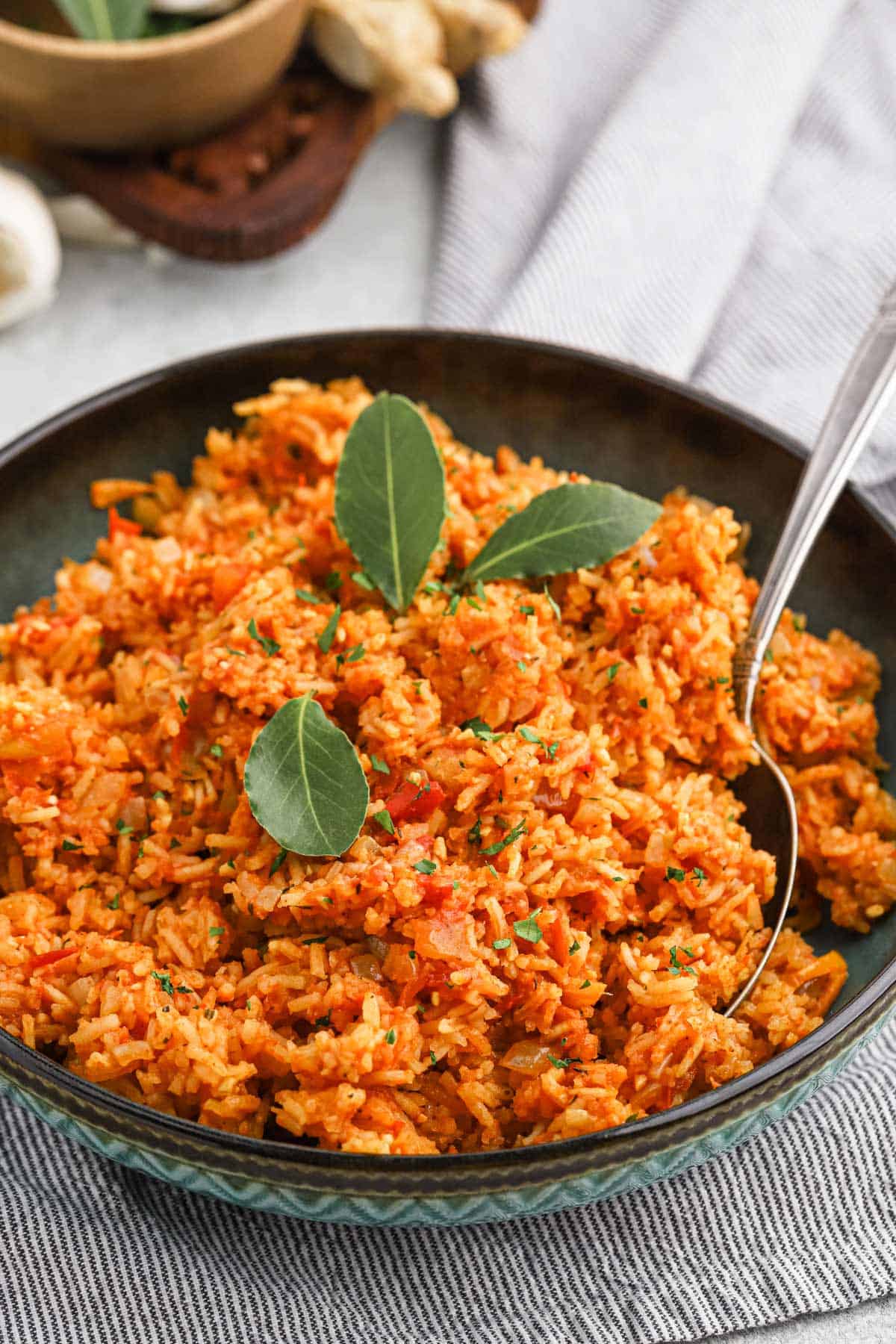 A bowl of easy jollof rice on the table with a spoon in the bowl.